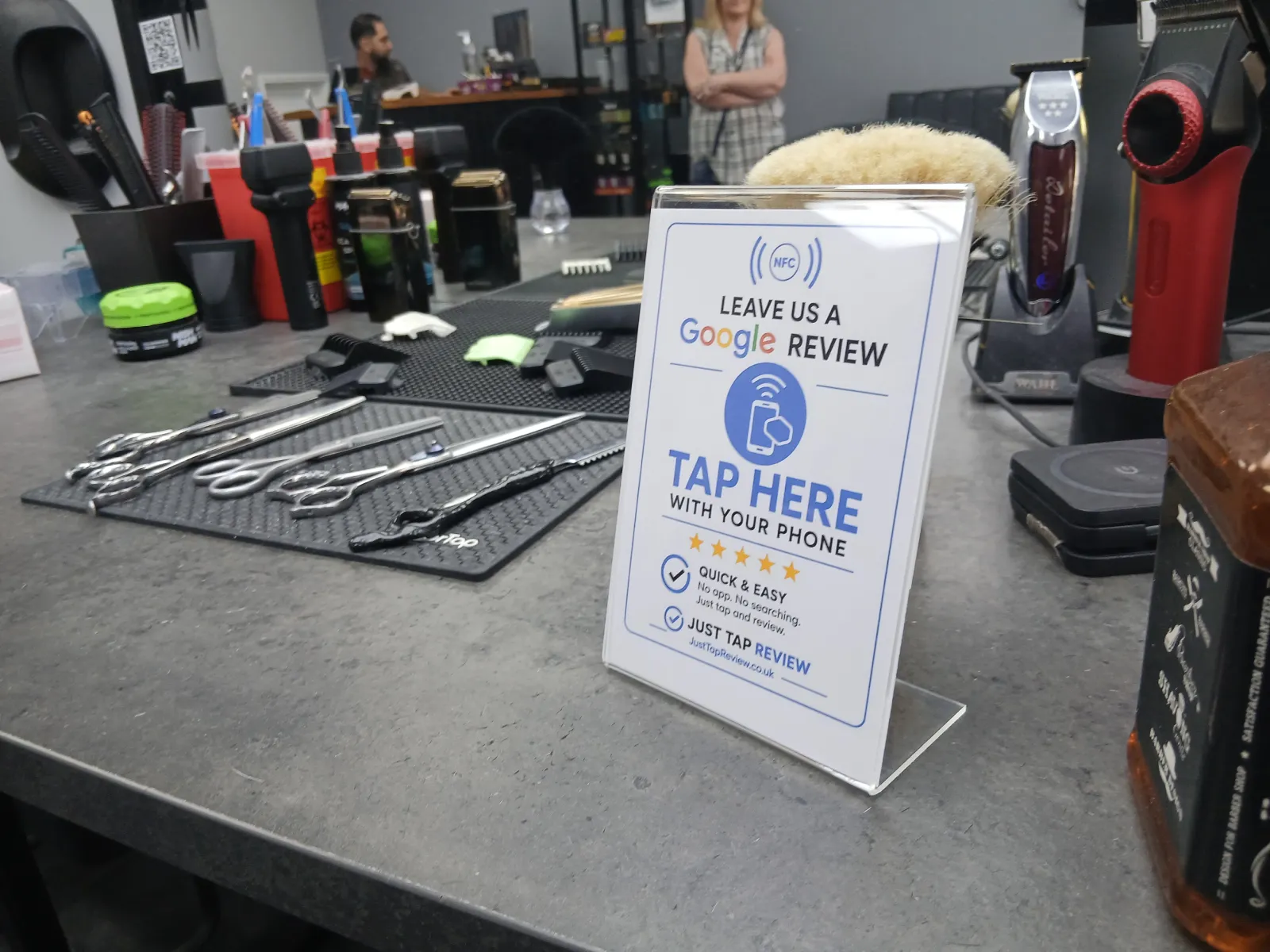 Google review stand displayed at a barber shop workstation